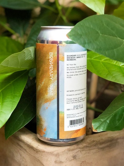 Colourful can of G.O.A.T. beer by Boundary brewing, surrounded by green leaves.