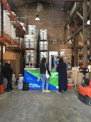 Inside of the brewery, a man pours two pints for two ladies waiting in line.